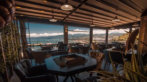 Un restaurante con vistas al mar y a las montañas, con muebles modernos y ventanas amplias.