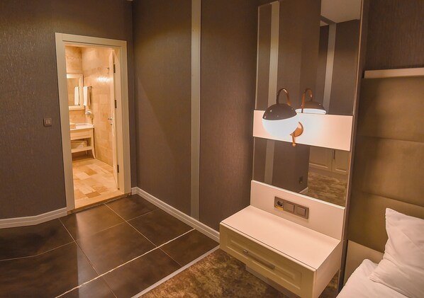 Una habitación de hotel con baño, cama y mesita de noche.