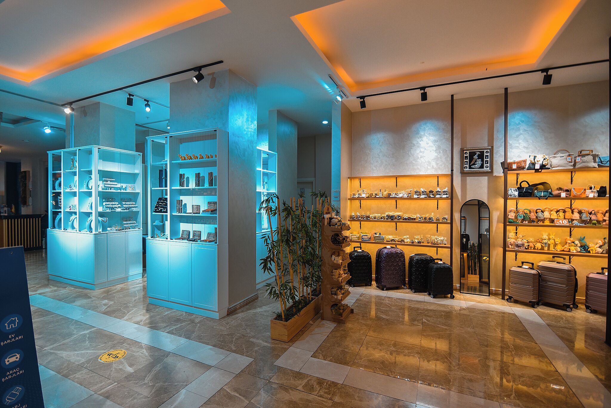 A modern hotel lobby with glass display cases, a central plant, and luggage racks.
