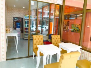 Une chambre d’hôtel avec un coin repas, un minibar et une vue sur la rue, visible à travers une porte vitrée.