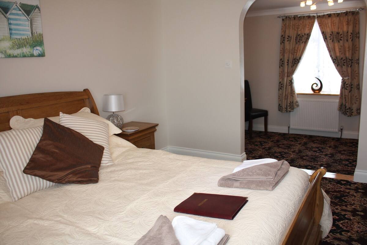 A neatly made bed with pillows, a bedside lamp, and a book on the nightstand.