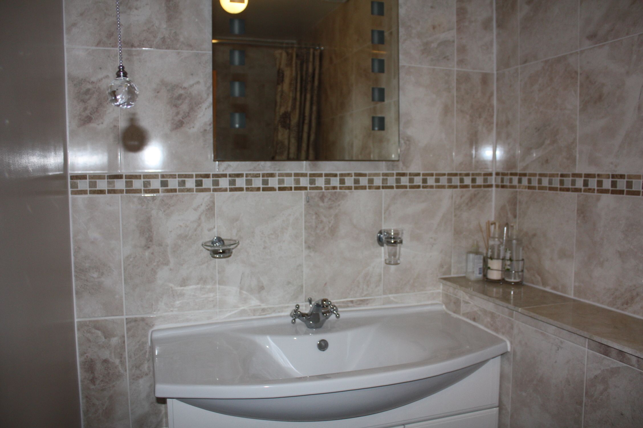 A bathroom with a white sink, a mirror, and a tiled backsplash.