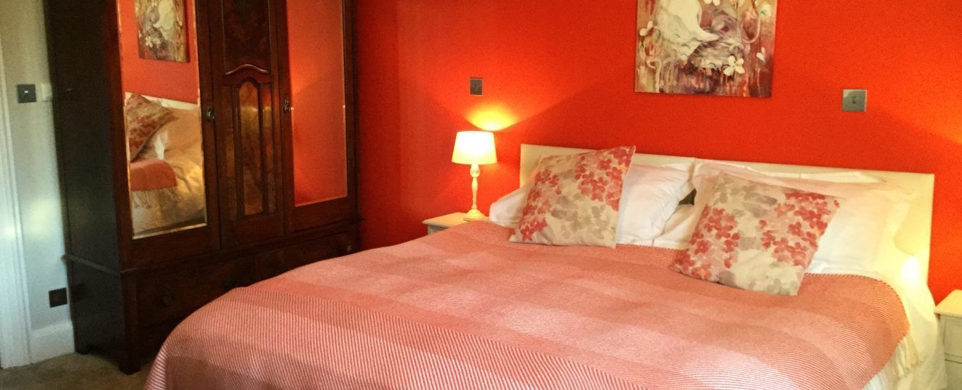 Une chambre à coucher avec un lit, une table de chevet, une lampe et un miroir.