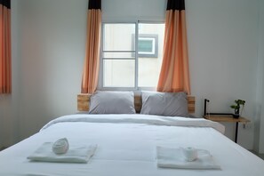 A neatly made bed with white linens, two pillows, and a rolled towel on a wooden nightstand beside it. - Rung Chiangrai Resort (Chiang Rai)