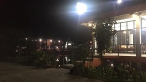 Ein Hotel bei Nacht, mit beleuchtetem Eingang und überdachtem Außenbereich mit Pflanzen.