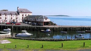 Un hotel costero con zona de embarcadero, barcos y un primer plano con césped.
