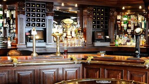 Un bar con mostradores de madera, múltiples grifos y una gran variedad de botellas.