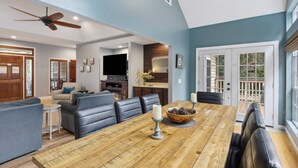 Ein geräumiges Wohnzimmer mit großem Holzesstisch, Ledersofas und Deckenventilator.