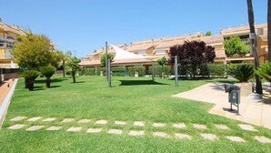 Un cortile curato con prato verde, un gazebo bianco e una fila di edifici sullo sfondo.