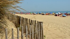 Una playa arenosa con cercas de madera y sombrillas de colores.