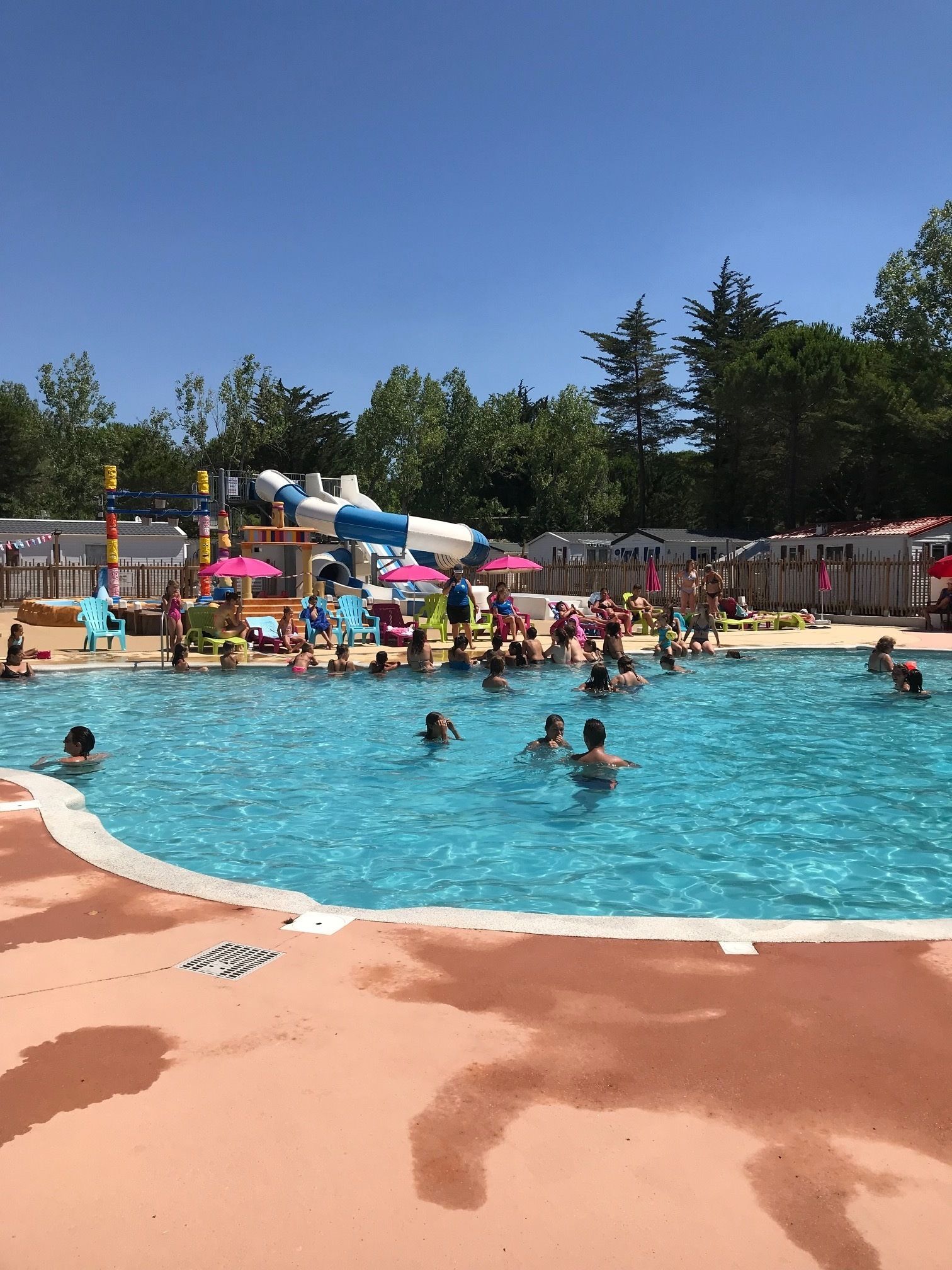 A swimming pool with a water slide and lounge chairs.
