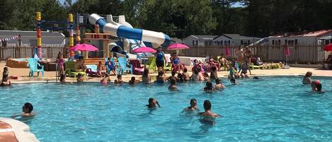A swimming pool with a water slide and lounge chairs.