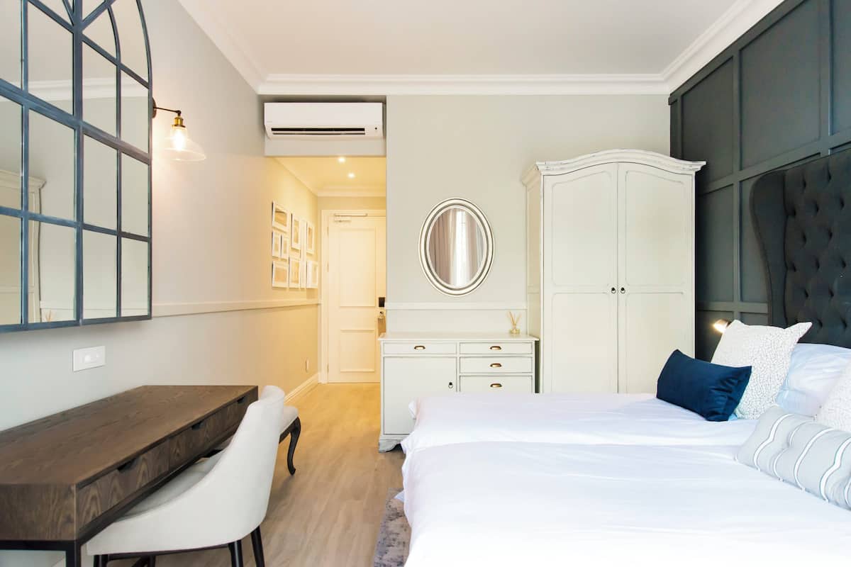 Un dormitorio con cama, escritorio, silla, armario y espejo.