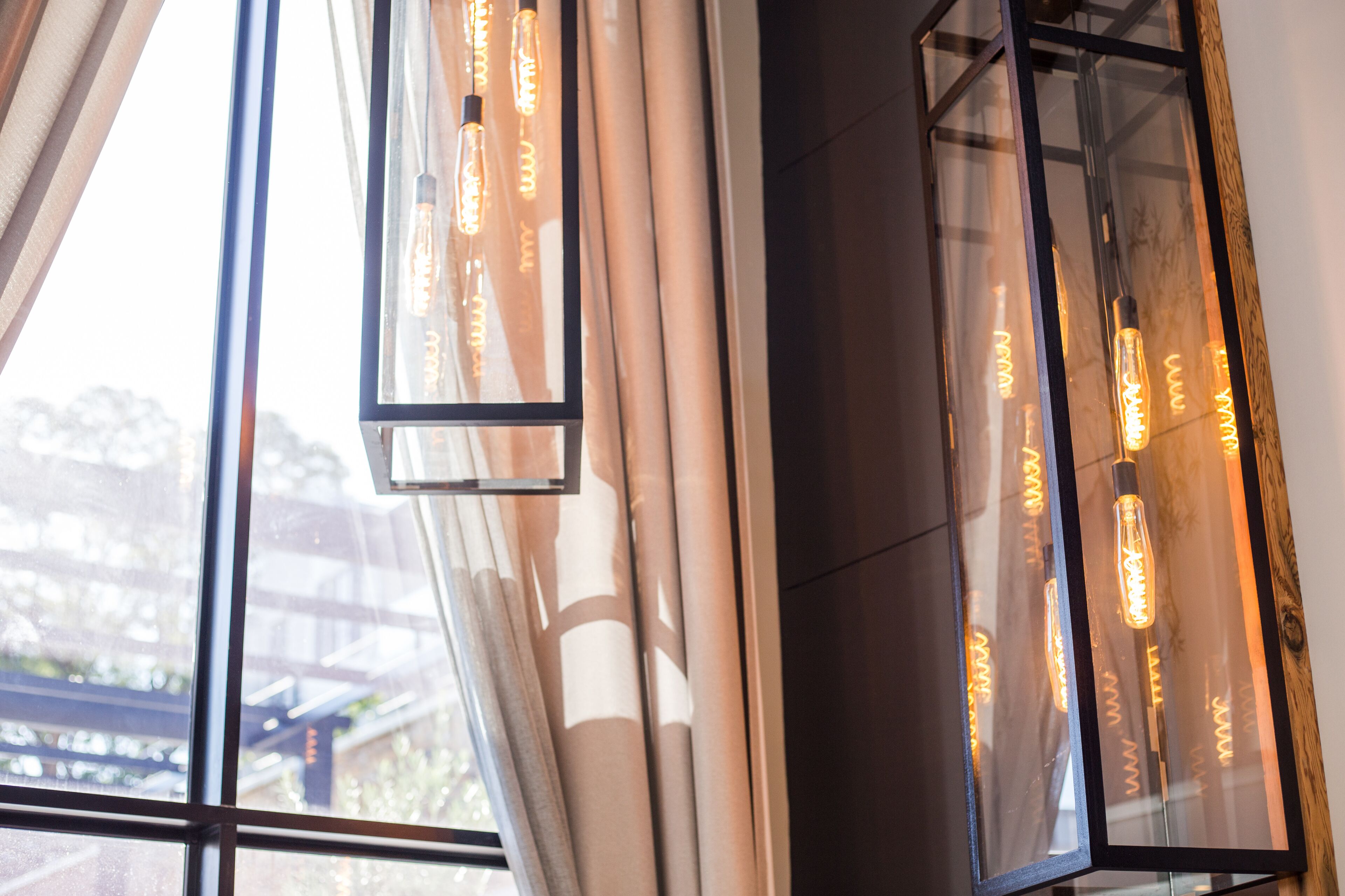 Un interior moderno con ventanas amplias, cortinas y lámparas colgantes.