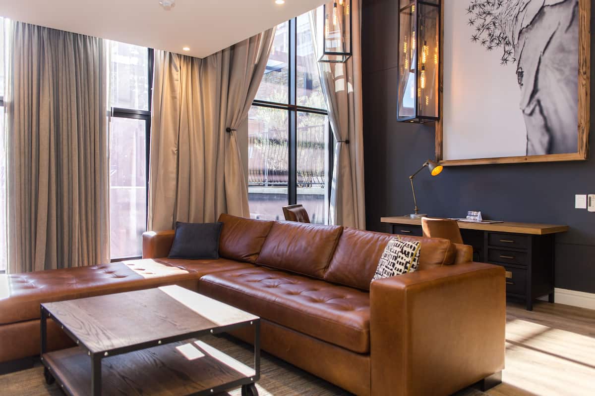 Una sala de estar moderna con un sofá de cuero, una mesa de centro de madera y un escritorio con una lámpara.
