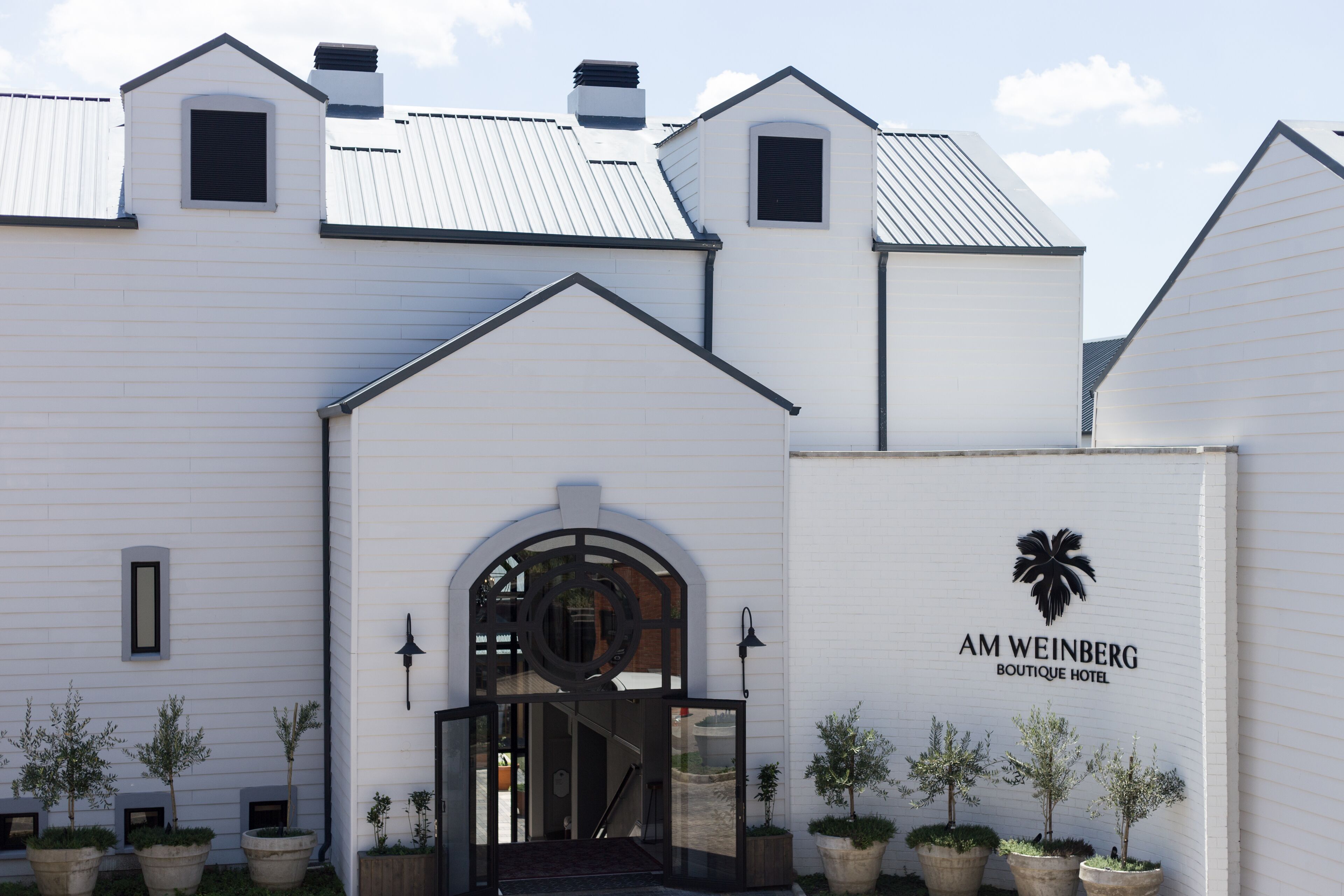 Un edificio blanco con un letrero que dice "AM WEINBERG BOUTIQUE HOTEL".