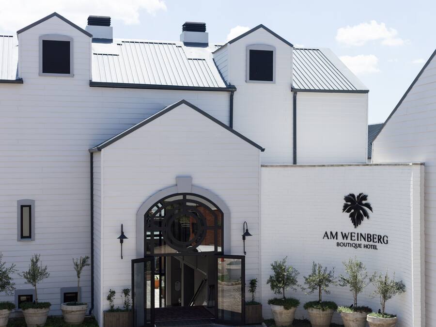 Un edificio blanco con un letrero que dice "AM WEINBERG BOUTIQUE HOTEL".