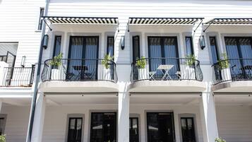A white building with multiple balconies, each with outdoor seating and potted plants.