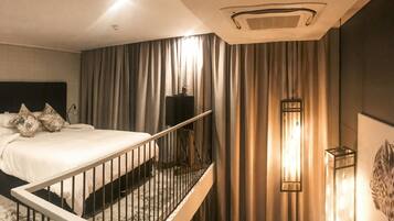Camera d'albergo con un letto, tende, una ringhiera, un punto luce a parete e una bocchetta di ventilazione al soffitto.