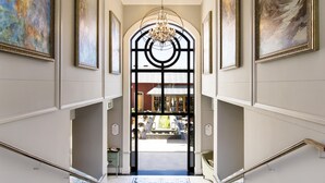 Une entrée somptueuse, agrémentée d’un lustre, d’un escalier et offrant une vue sur l’espace extérieur.