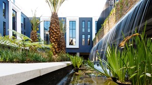 Un bâtiment moderne agrémenté d’un élément aquatique et de verdure.