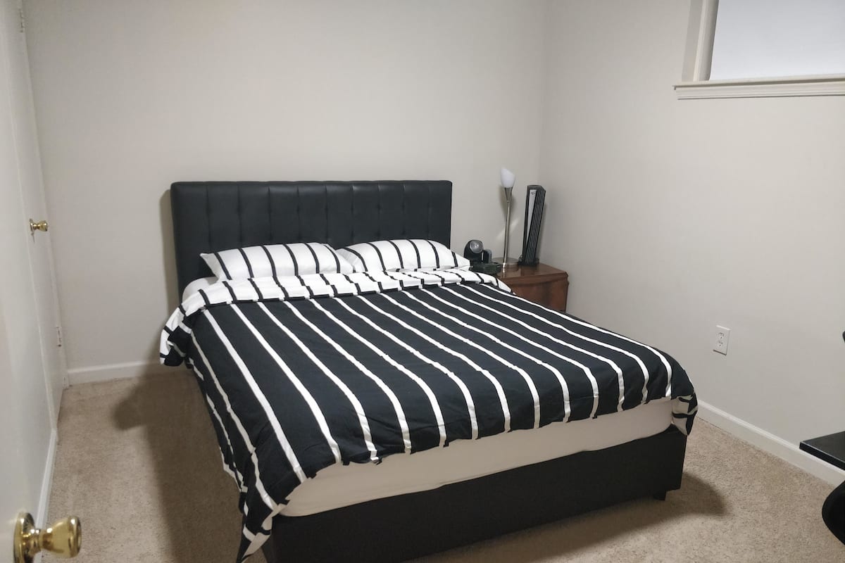 A bedroom with a bed, a nightstand, a lamp, and a door.