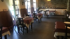 Ein Restaurant mit Holztischen und -stühlen, einer Steinwand und einer Wanduhr.