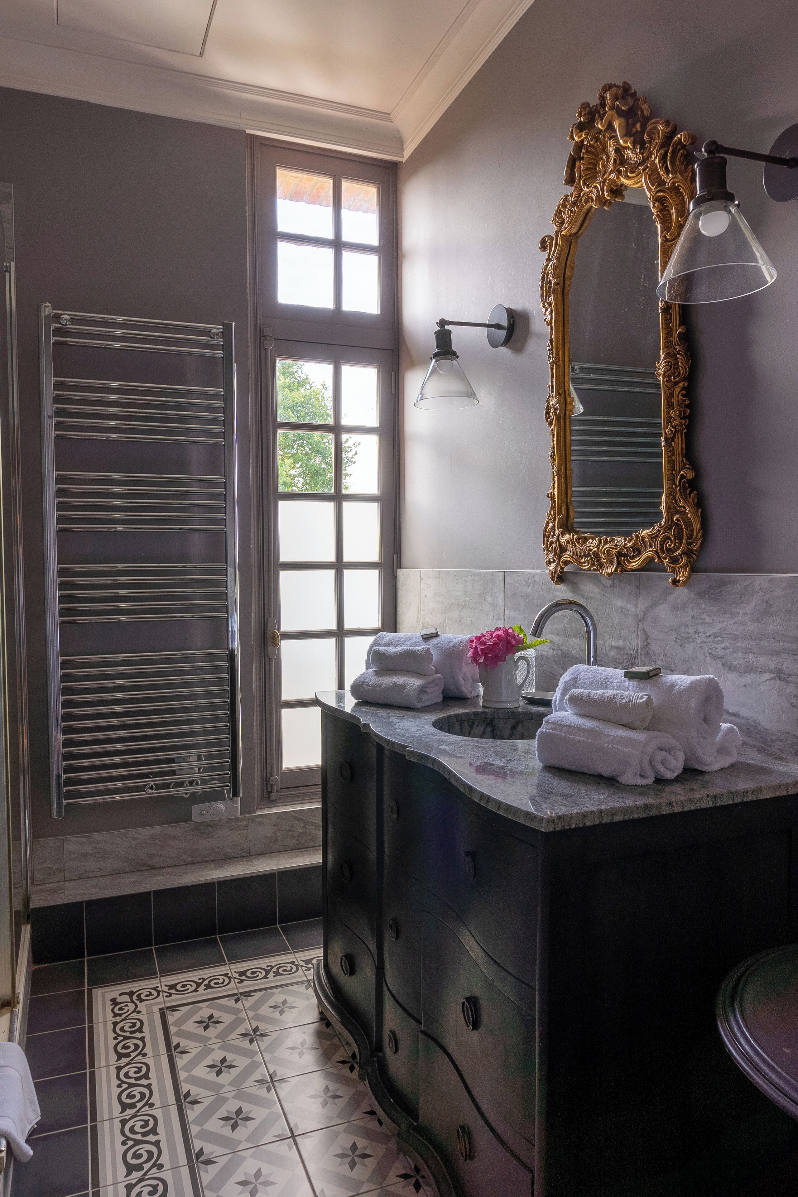 A bathroom with a large mirror, a sink with towels, and a window with blinds.