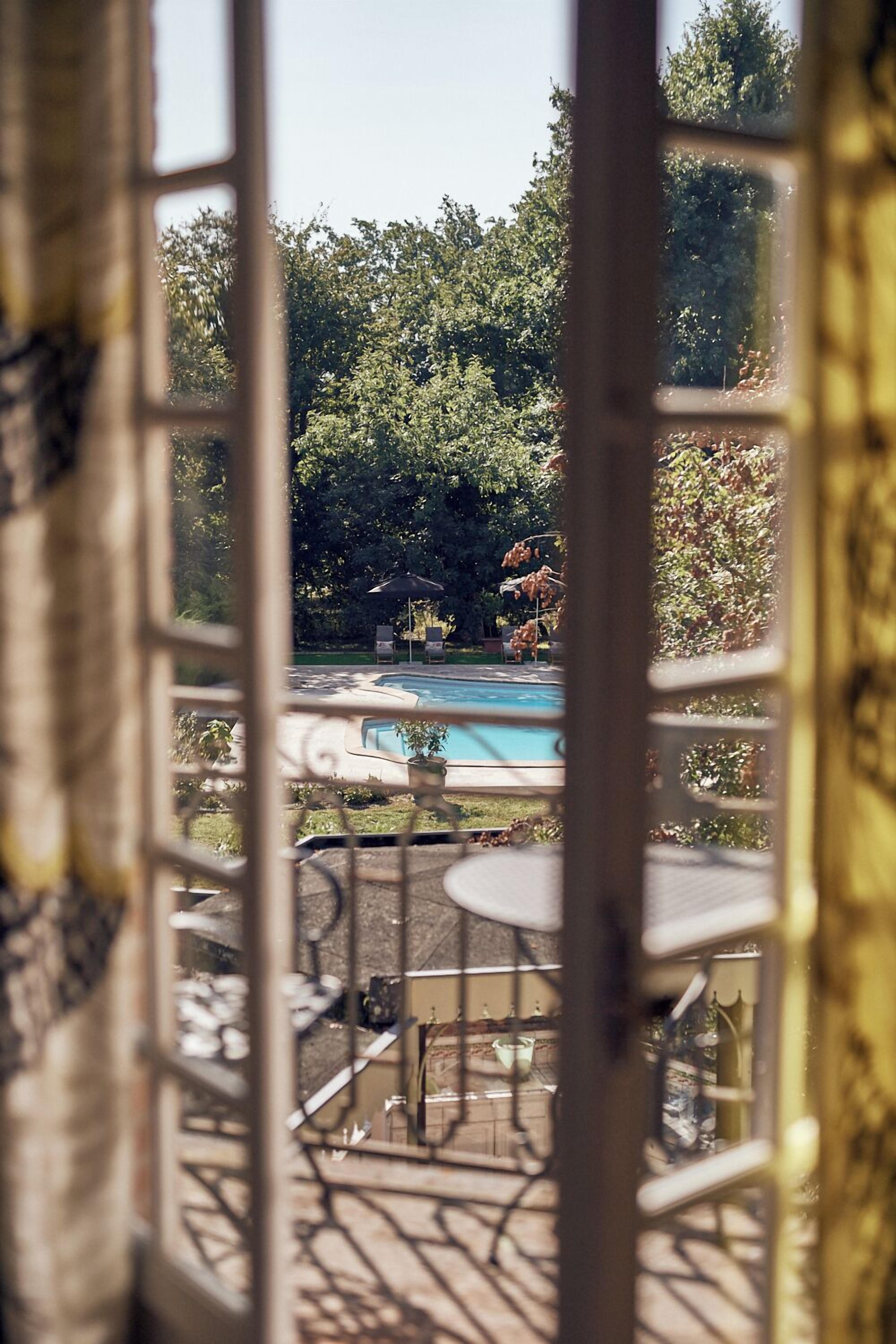 Ein Terrassenbereich im Freien mit Pool, umgeben von üppiger Vegetation und blauem Himmel.