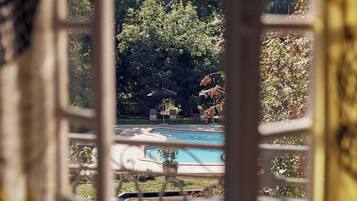 Ein Terrassenbereich im Freien mit Pool, umgeben von üppiger Vegetation und blauem Himmel.