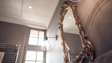An ornate mirror with intricate designs, a modern light fixture, and a window with multiple panes.