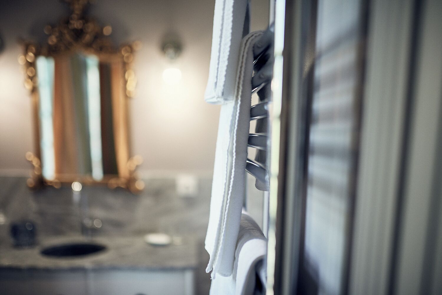 A bathroom with a mirror, a sink, and a towel rack.