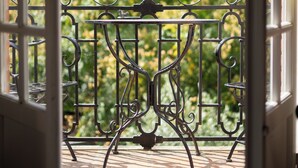 An open door leading to a balcony with a wrought iron railing and a small table. - Castel Bois Marie (Montauban)