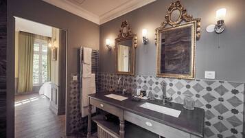 Un baño con dos lavamanos, espejos decorativos y un salpicadero de azulejos estampados.
