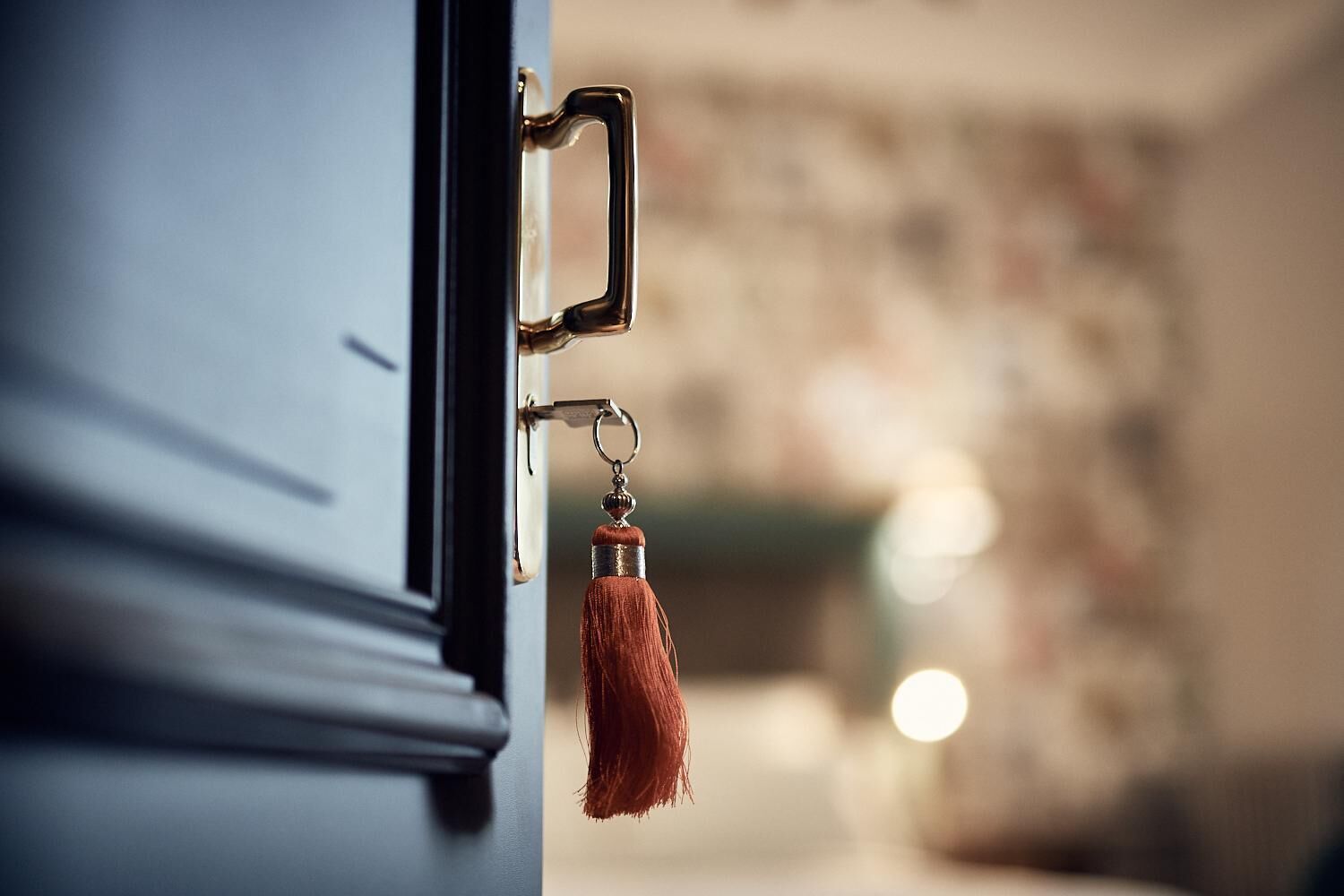 A door with a brass handle and a keychain with a tassel.