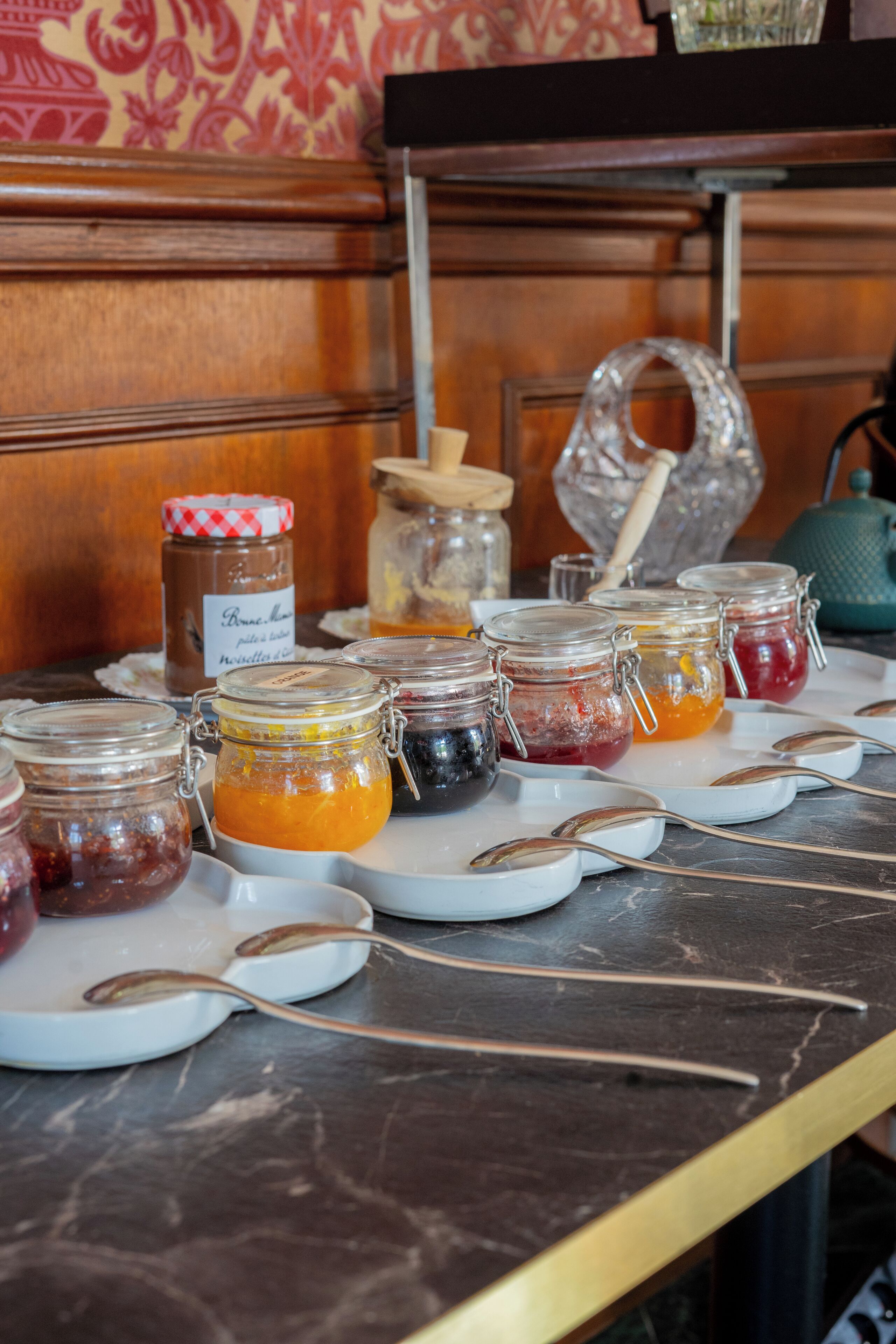 Une table de buffet avec différents pots contenant des aliments et des cuillères.