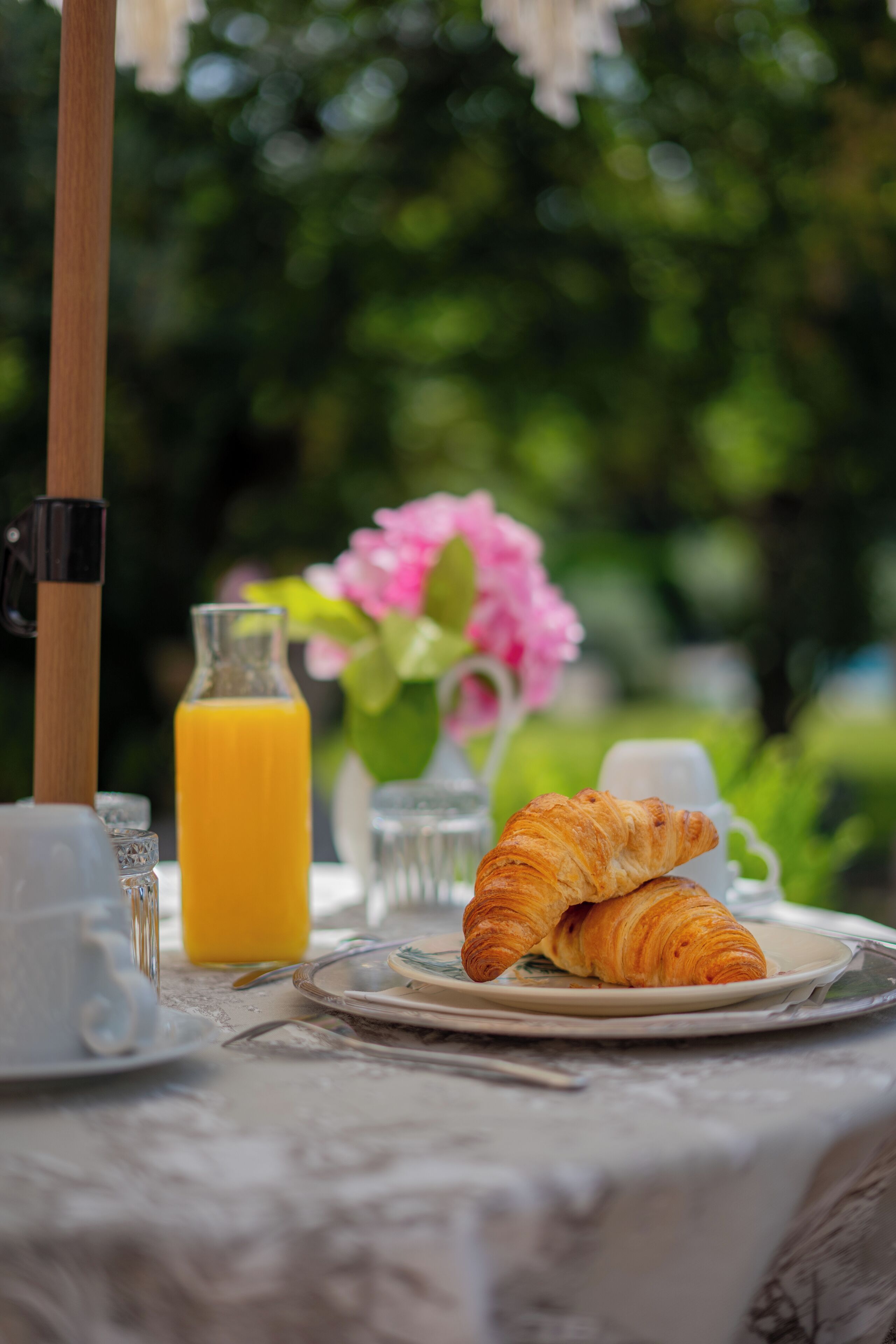 A breakfast table with croissants, a glass of orange juice, and a white cup.