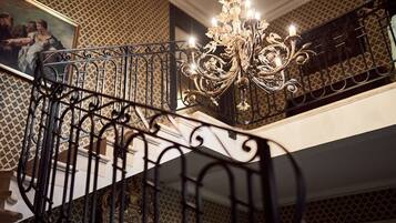 A staircase with ornate black metal railings and a chandelier.