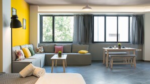 A modern living room with a sofa, a dining table, and a bench. - Eternal luxury suites (Athens)