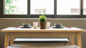 A table with two bowls and a woven pot with green plants, set against a window with a view of buildings. - Eternal luxury suites (Athens)