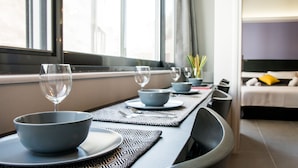 A modern dining area with a long table set for two, featuring a patterned placemat and matching bowls and plates. - Eternal luxury suites (Athens)