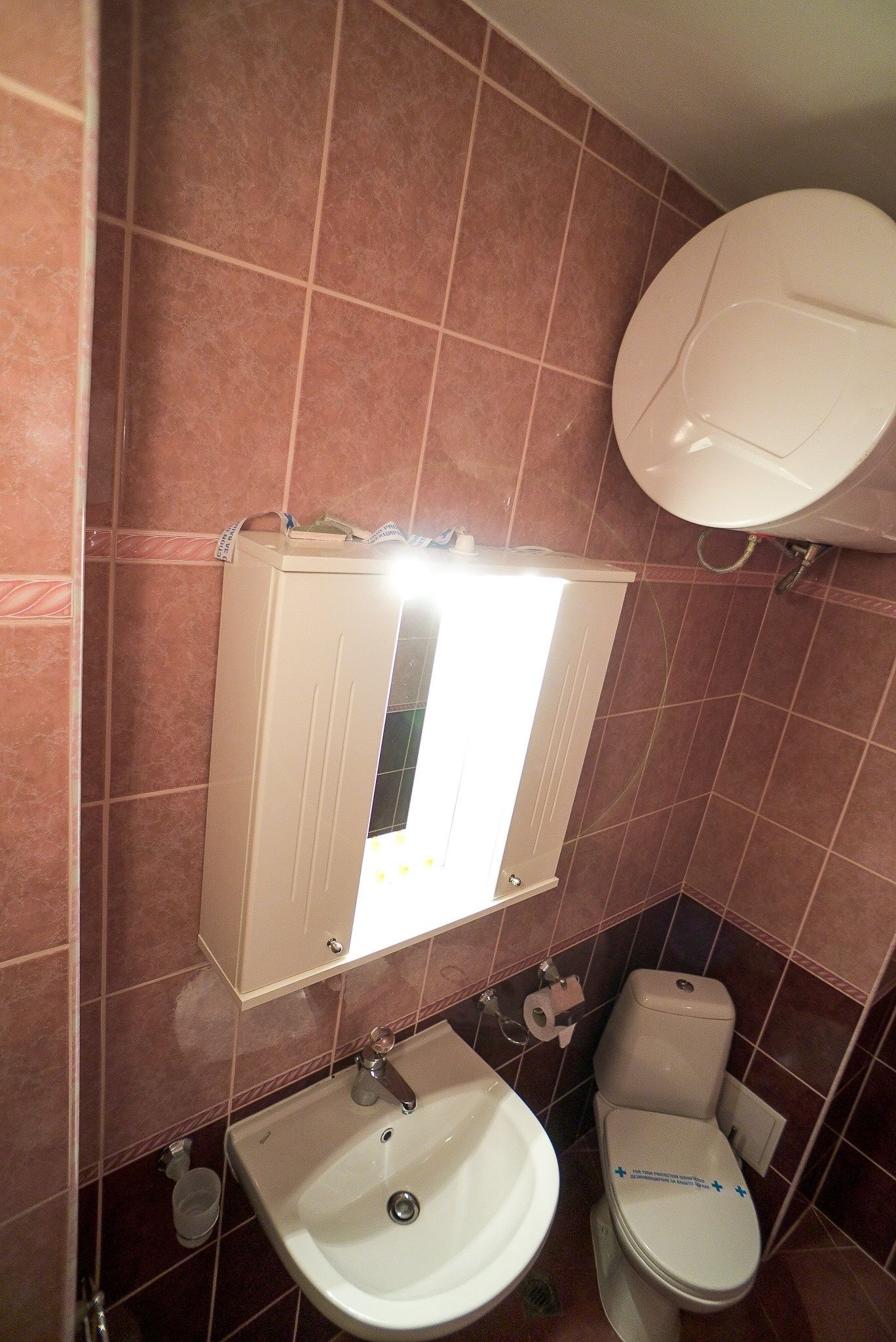 A bathroom with a sink, toilet, and mirror.