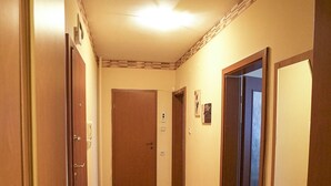 A hallway with wooden flooring, a bench, and doors leading to other rooms. - Apartment Geo Milev (Plovdiv)