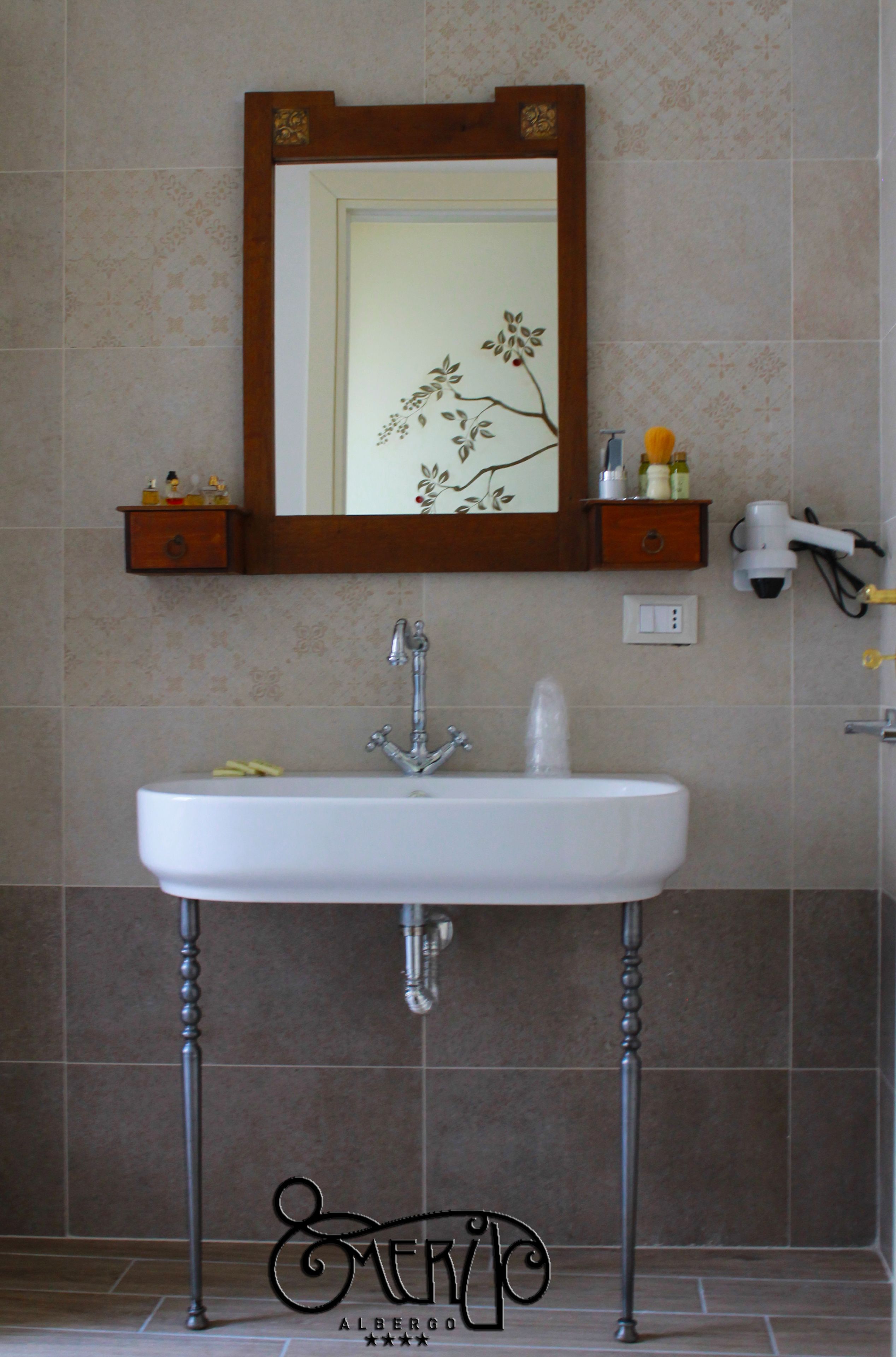 Un baño con un lavamanos blanco, un espejo con marco decorativo y un perchero para toallas.