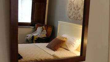 Une chambre avec un grand miroir, un lit avec des oreillers, un globe terrestre et une carte sur la table.