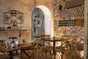 Un comedor rústico con muebles de madera, pared de piedra y detalles decorativos en metal.