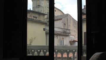 Une pièce dont la porte est ouverte et qui donne sur un balcon offrant une vue sur de vieux bâtiments.