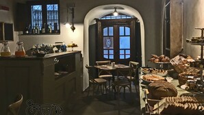 A cozy dining area with a rustic wooden table, chairs, and a variety of breads and pastries.