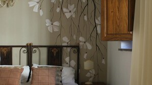 A neatly made bed with a patterned bedspread, two pillows, and a bedside table with a lamp.