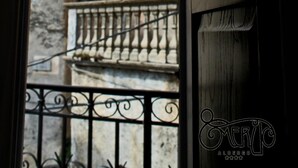 A balcony with wrought iron railings and a view of historic stone buildings.
